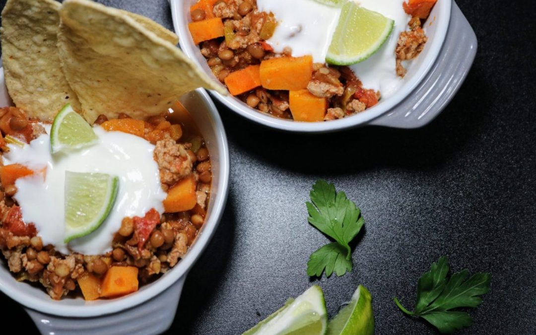 Chili à la dinde, patates douces et lentilles servi avec crème sure, lime et chips de mais