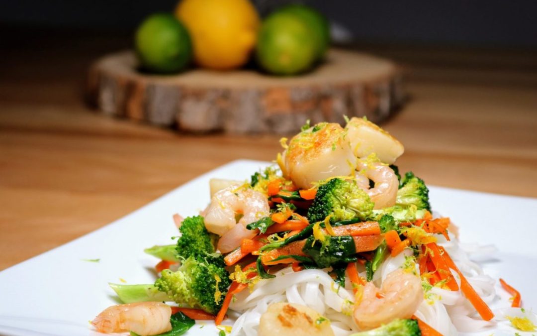 Sauté de crevettes et pétoncles aux agrumes avec brocolis et carottes servi sur vermicelles