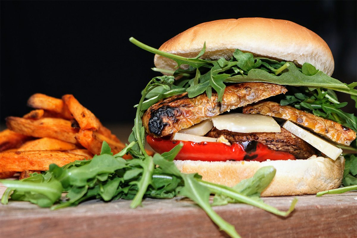 Hamburger de tempeh garni de poivron rouge, champignon, fromage et roquette accompagné de patates douces