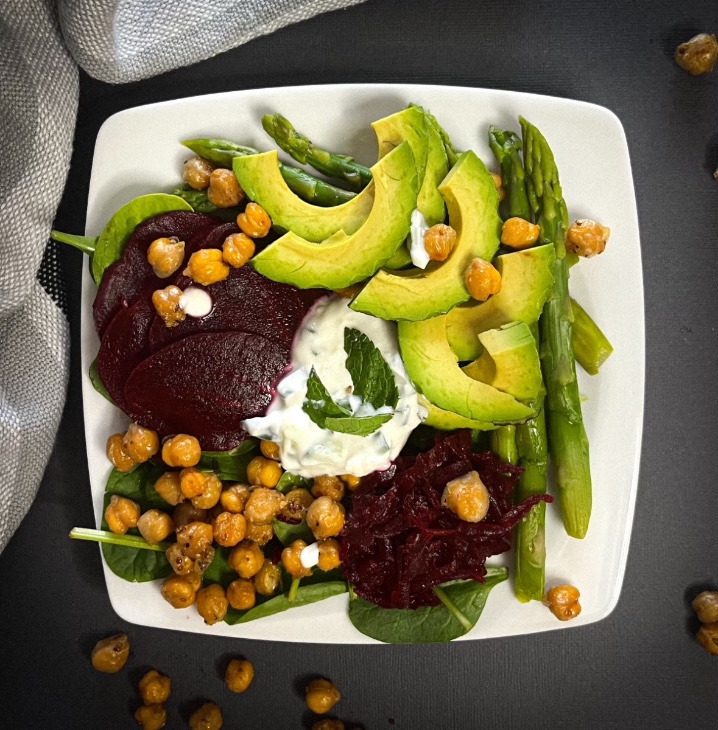 Salade prébiotique composée d'asperges, de betteraves, d'avocat et de verdures avec pois chiches rôtis à l'érable et sauce à l'ail